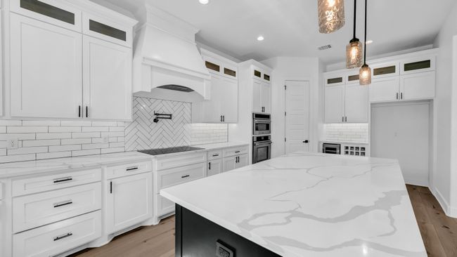 Kitchen featuring light wood-style flooring, a kitchen island, white cabinetry, custom exhaust hood, and hanging light fixtures | Image 19