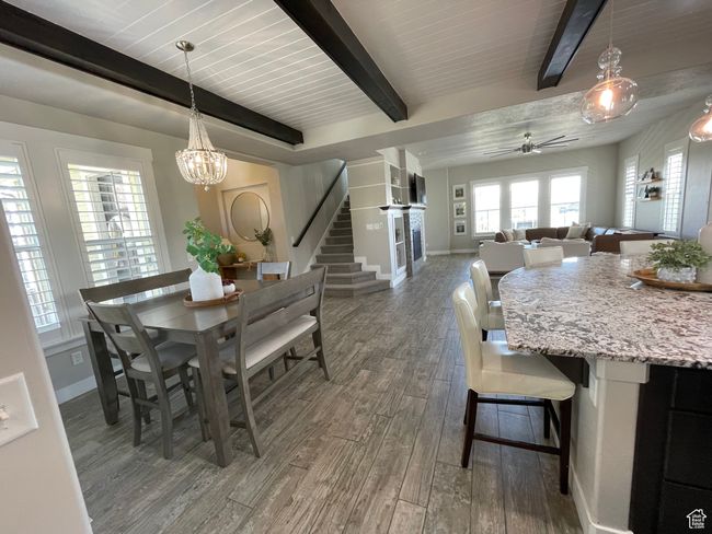 Dining space featuring wood-style tile, beamed ceiling, baseboards, stairs, and ceiling fan with notable chandelier | Image 16