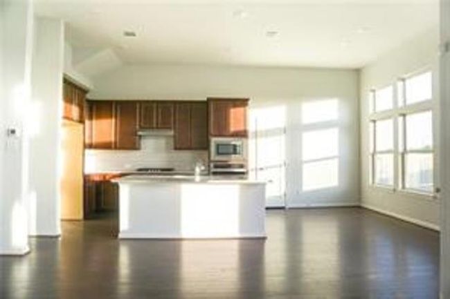 Kitchen featuring white microwave, healthy amount of natural light, light countertops, and a kitchen island with sink | Image 7