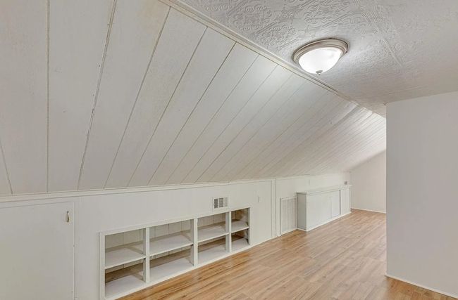 Additional living space with a decorative wall, wood finished floors, and lofted ceiling | Image 13