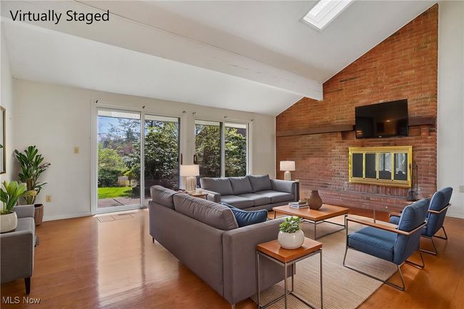 Living room with baseboards, vaulted ceiling with beams, wood finished floors, and a brick fireplace | Image 7