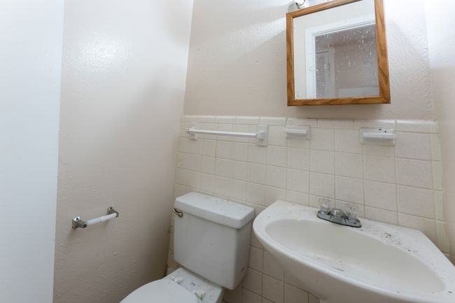 Half bathroom with a sink, a wainscoted wall, toilet, and tile walls | Image 9