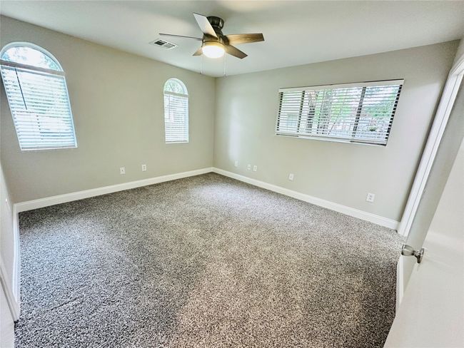 Empty room featuring healthy amount of natural light, ceiling fan, and carpet | Image 11
