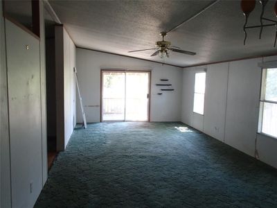 Empty room featuring a wealth of natural light, ceiling fan, and carpet floors | Image 2