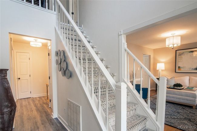 Staircase with wood finished floors, visible vents, a towering ceiling, and baseboards | Image 4