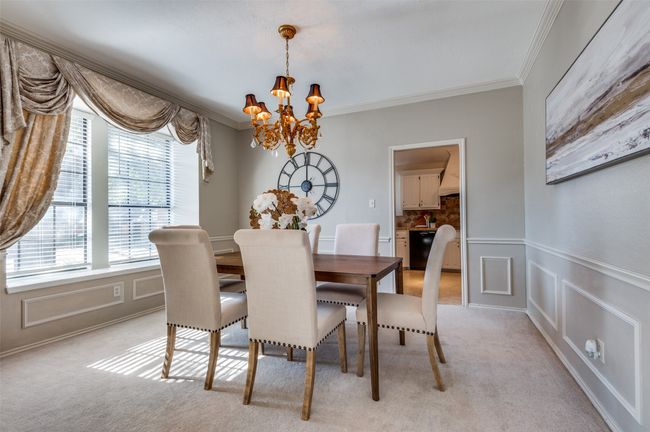 Dining room featuring light carpet, a wainscoted wall, crown molding, a chandelier, and a decorative wall | Image 8