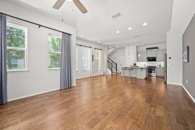 Unfurnished living room featuring ceiling fan, wood finished floors, recessed lighting, and stairs | Image 8