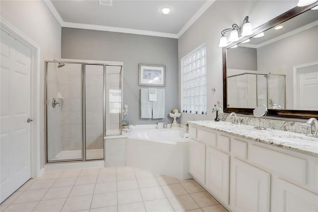The primary bathroom boasts a large dual-sink vanity with granite countertop, a glass-enclosed shower with a built-in bench seat, and a separate jetted bathtub. | Image 20