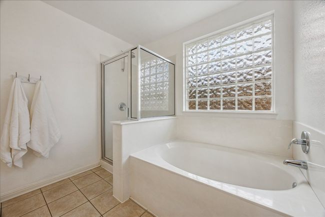 Primary bathroom featuring healthy amount of natural light, a garden tub, a stall shower, and tile flooring | Image 17
