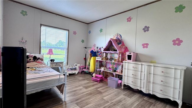 Bedroom with wood finished floors and crown molding | Image 22