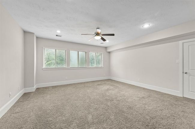 This upstairs game room is a great hangout spot—plenty of open space for a pool table, media center, or play area. The carpet keeps it cozy, and the row of windows brings in natural light so it never feels dark or cramped. Perfect for family movie nights, gaming sessions, or a kids’ homework zone. | Image 24