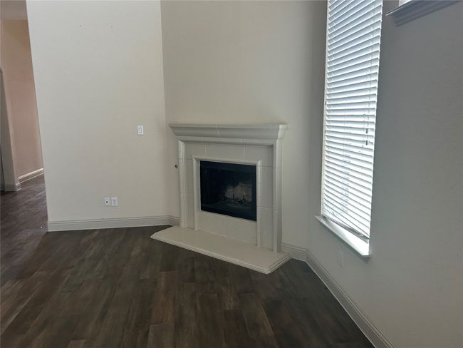 Detailed view of wood finished floors, a tiled fireplace, and baseboards | Image 6