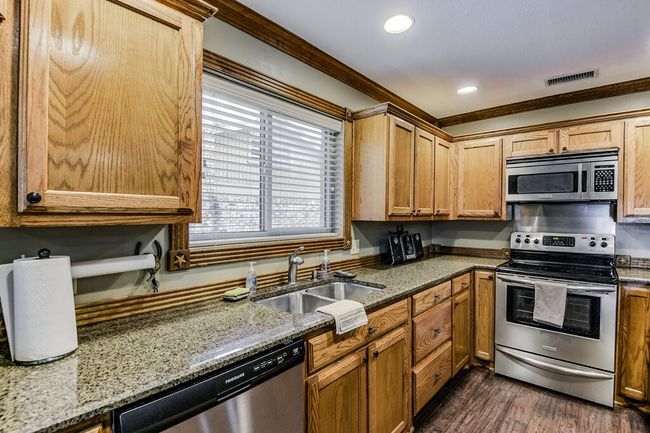Kitchen featuring appliances with stainless steel finishes, ornamental molding, dark wood finished floors, stone countertops, and recessed lighting | Image 12