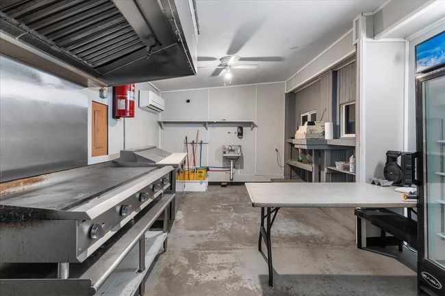 Kitchen featuring unfinished concrete flooring, ceiling fan, exhaust hood, and a wall mounted AC | Image 26
