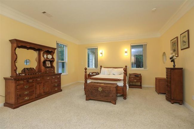 Huge Primary bedroom suite that features double crown molding, carpet, attractive wall sconces, and plenty of windows for natural light. | Image 31