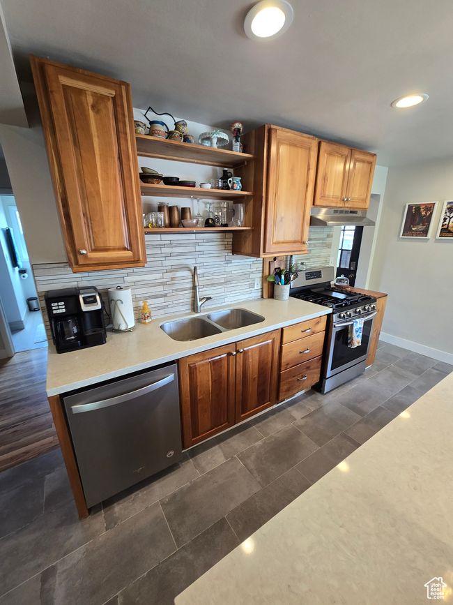 Kitchen with open shelves, under cabinet range hood, appliances with stainless steel finishes, backsplash, and a sink | Image 17
