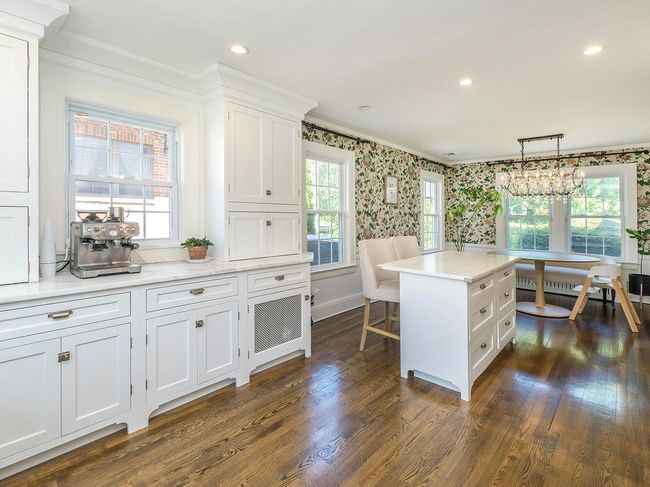 Kitchen featuring white cabinetry, wallpapered walls, crown molding, light countertops, and healthy amount of natural light | Image 7