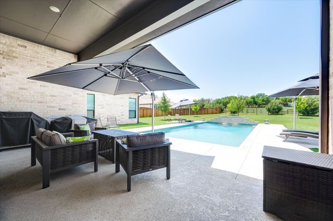 View of swimming pool featuring a fenced in pool, a lawn, a fenced backyard, a patio area, and a grill | Image 30