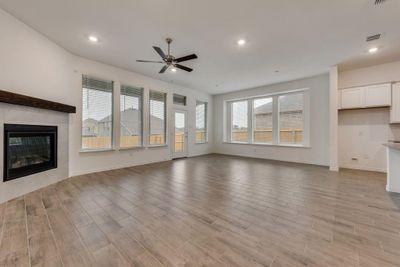 Unfurnished living room with ceiling fan, a fireplace, and light hardwood / wood-style flooring | Image 2