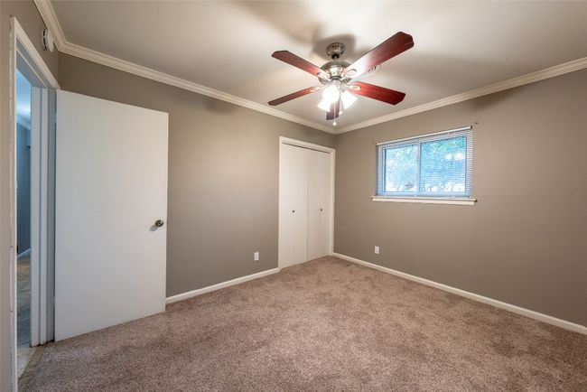 Unfurnished bedroom featuring carpet, ornamental molding, a closet, and ceiling fan | Image 26