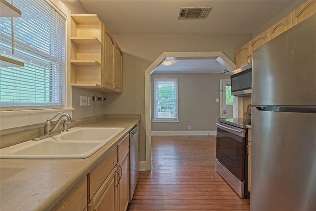 Kitchen with appliances with stainless steel finishes, wood finished floors, open shelves, light countertops, and light brown cabinets | Image 16