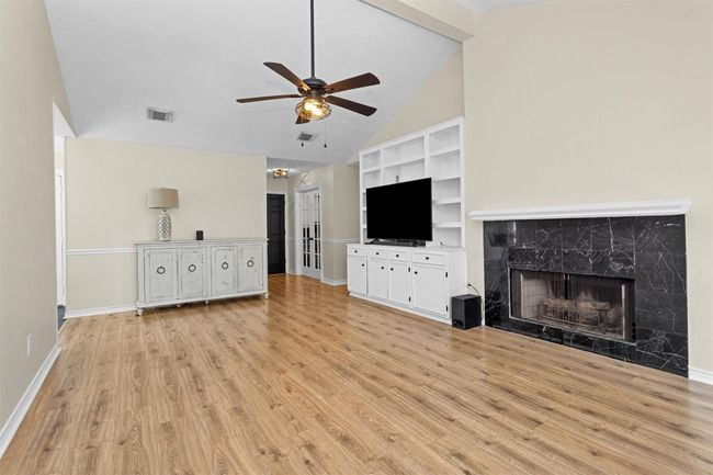 This spacious living room offers warmth and character with a cozy fireplace as its focal point, perfect for relaxing evenings. A custom built-in credenza also adds both style and storage. | Image 5