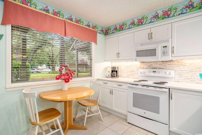Kitchen featuring white appliances, light countertops, white cabinets, light tile patterned flooring, and a textured ceiling | Image 9