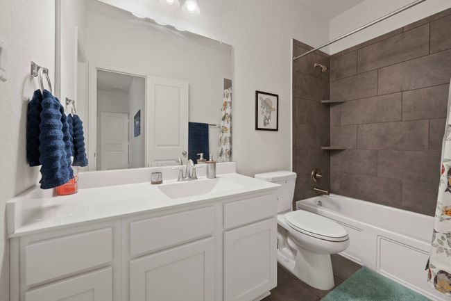 Bathroom with toilet, vanity, shower / bathtub combination with curtain, and tile patterned flooring | Image 16