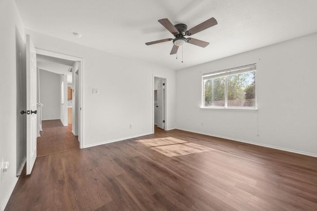 Unfurnished primary bedroom featuring baseboards, wood finished floors, and a ceiling fan | Image 12