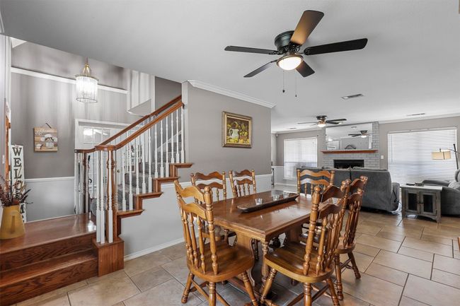 Tiled dining area featuring brick wall, ornamental molding, a fireplace, and ceiling fan | Image 11