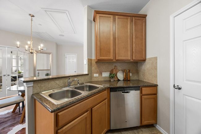 Kitchen featuring stainless steel dishwasher, tile backsplash, brown cabinets. | Image 13