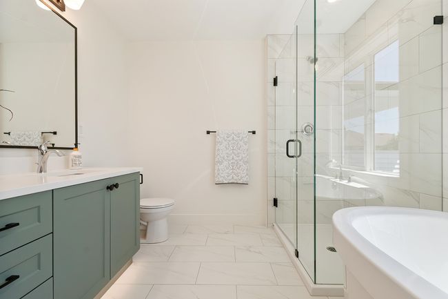 Full bath featuring vanity, a bath, a shower stall, and marble look tiles | Image 23