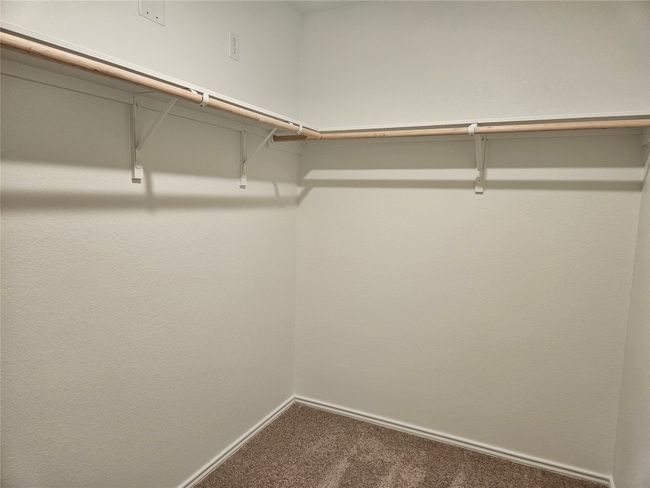 Walk in closet featuring dark colored carpet | Image 10