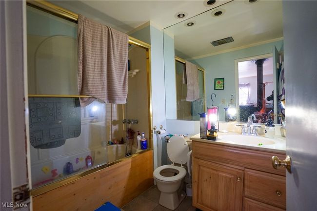 Bathroom featuring tile patterned floors, toilet, visible vents, vanity, and enclosed tub / shower combo | Image 19