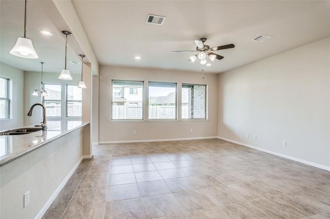 Spacious, family room with tile flooring, ceiling fan, and plenty of windows to provide natural light. | Image 12