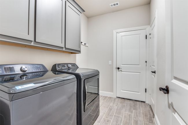 Washroom featuring washing machine and dryer, cabinet space, and wood finish floors | Image 32