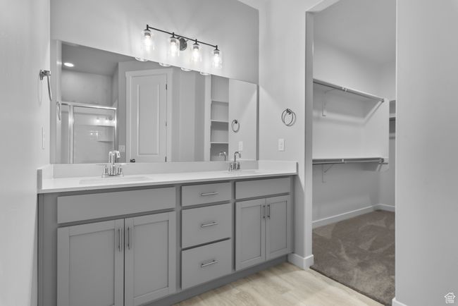 Full bathroom featuring double vanity, a shower stall, a spacious closet, and wood finished floors | Image 11