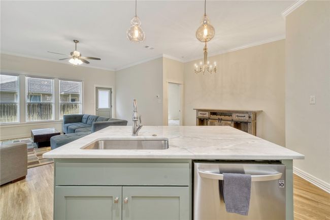 Kitchen featuring stainless steel dishwasher, open floor plan, light wood-type flooring, a ceiling fan, and ornamental molding | Image 11
