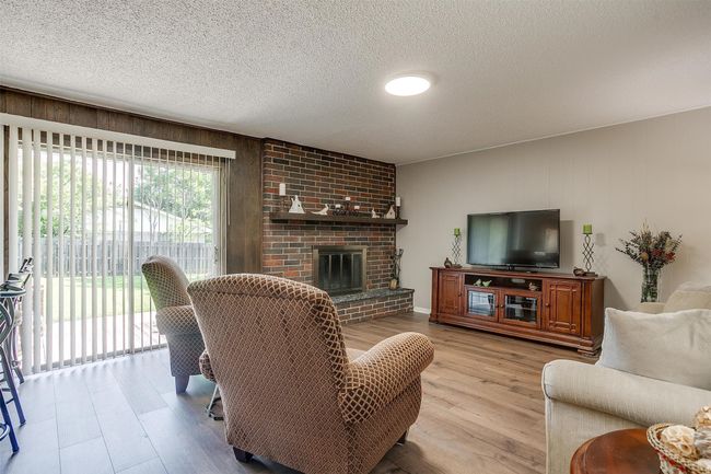 Living room with wood finished floors, a brick fireplace, a textured ceiling, and wooden walls | Image 12