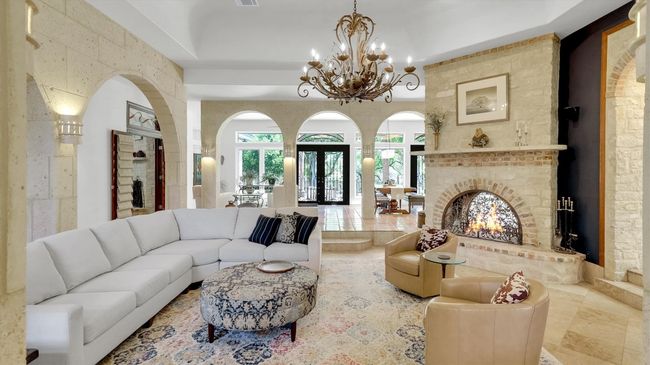 Living room featuring a chandelier, plenty of natural light, arched walkways, and a fireplace | Image 7