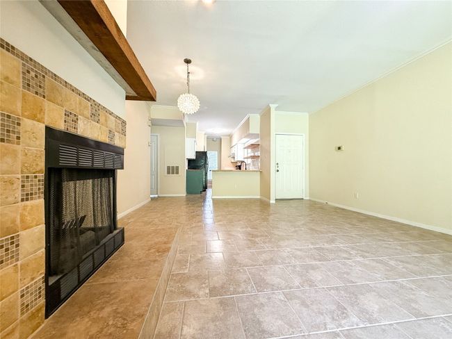 Unfurnished living room with a tiled fireplace, ornamental molding, and light stone finish flooring | Image 11