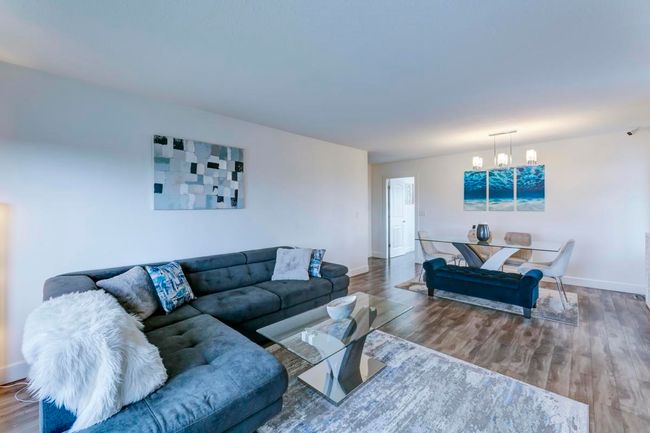 Living area featuring baseboards, a notable chandelier, and wood finished floors | Image 4