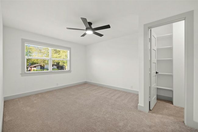 The spacious owner's retreat has a large walk-in closet, tall baseboards, a nice ceiling fan and a pocket door that leads into the primary's ensuite bathroom. | Image 17