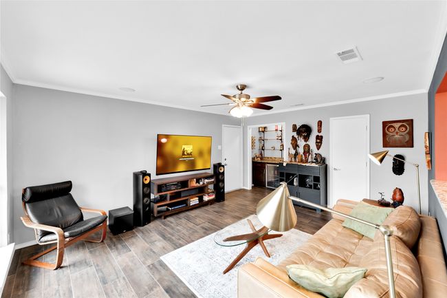 Living area with wine cooler, a ceiling fan, wood finished floors, and crown molding | Image 5