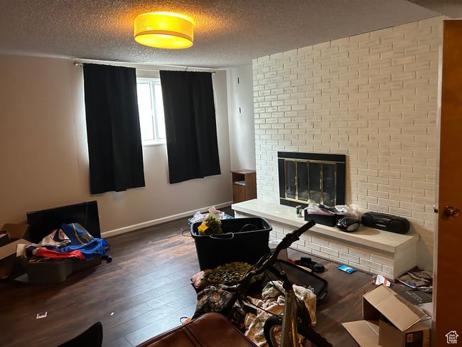 Office area featuring hardwood / wood-style flooring, a textured ceiling, baseboards, and a brick fireplace | Image 8