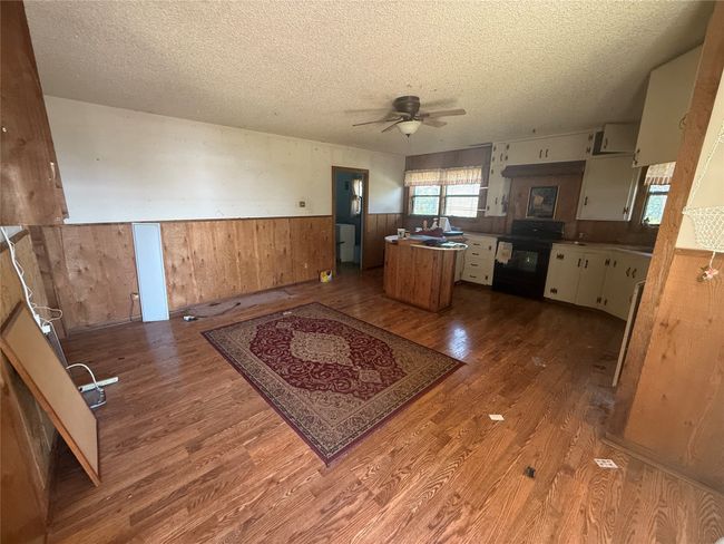 Kitchen with wainscoting, a textured ceiling, wood finished floors, ceiling fan, and dishwasher | Image 6