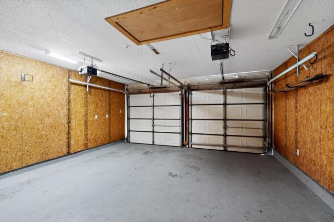 Garage featuring a garage door opener and wooden walls | Image 34