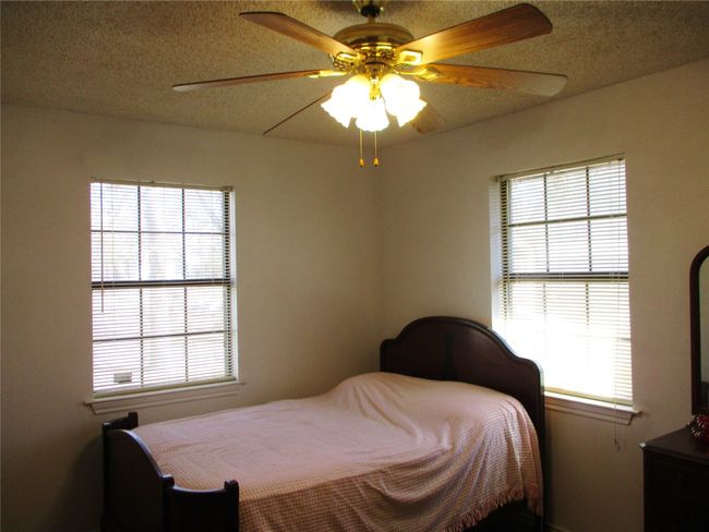 Bedroom with a ceiling fan and a textured ceiling | Image 13