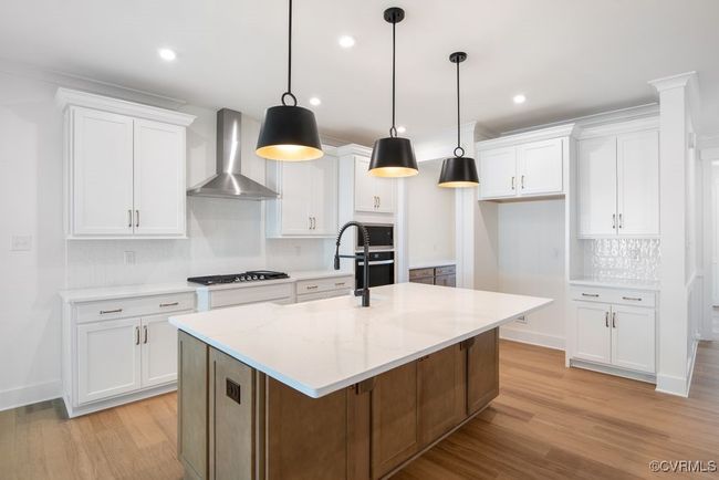 Photo represents the plan, not the actual home. Design selections may vary. A spacious kitchen with an island and pantry open to an adjoining dining area and the family room. | Image 7