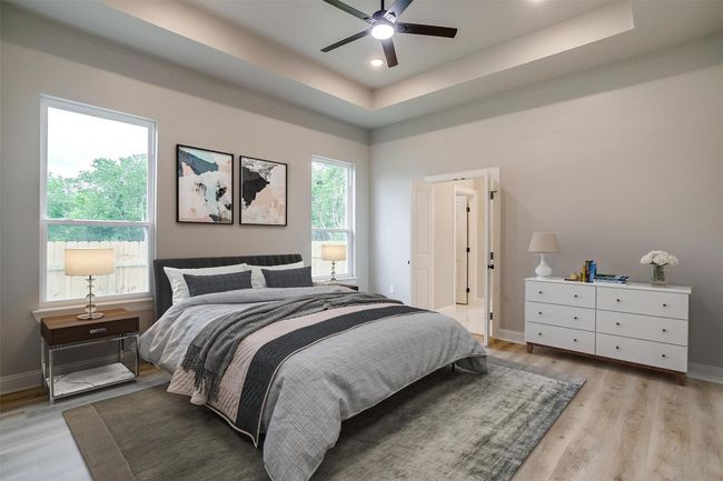 Bedroom with light wood-type flooring, baseboards, and a tray ceiling | Image 16